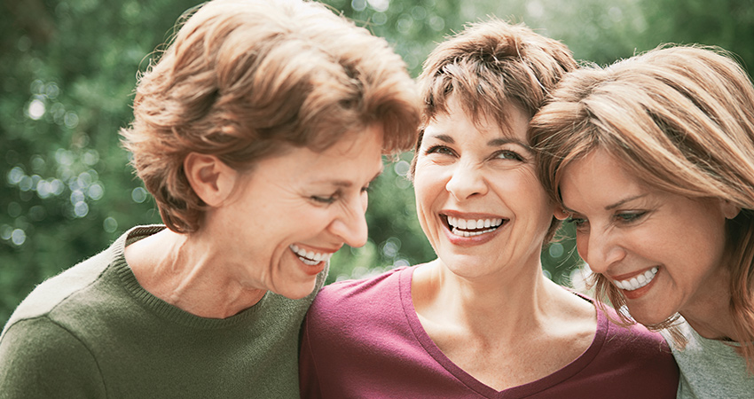 Three women with dental implants smile
